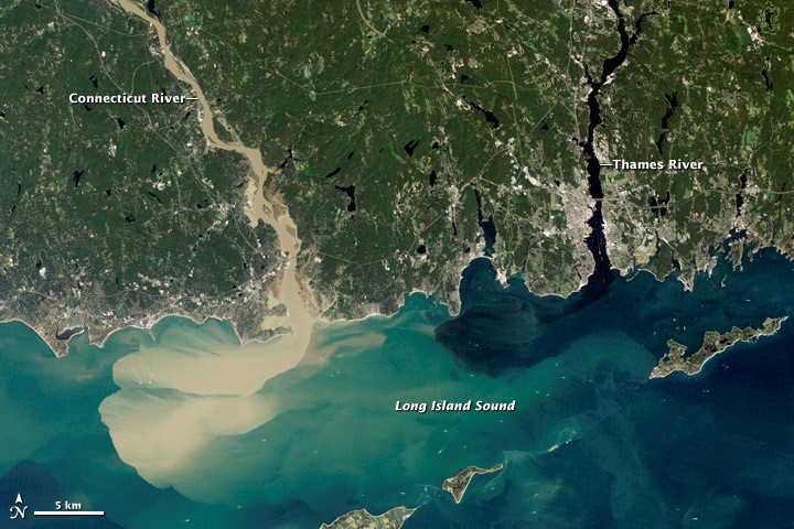 Аэроснимок с Новой Англии, показывающий впадение половодной реки в океан. Вода коричневая из-за наличия осадка